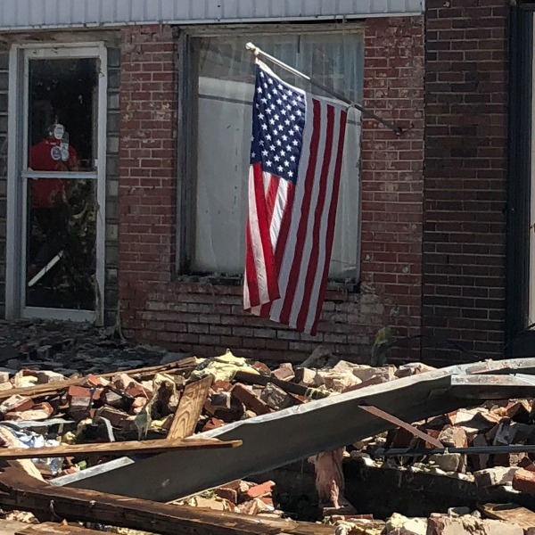 image of house with damage with American flag